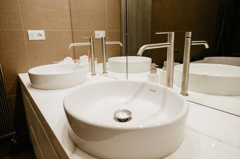 Custom bathroom vanity. Detail of Calacatta countertop with double sink and stainless steel fixtures